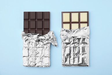 Photo of Tasty chocolate bars on light blue background, flat lay