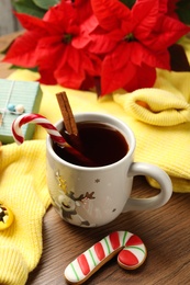Photo of Composition with cup of hot drink and yellow sweater on wooden table