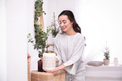 Woman decorating home interior with eucalyptus branches