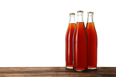 Photo of Bottles of delicious kvass on wooden table against white background