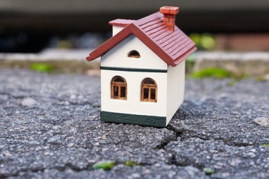 House model on cracked asphalt. Earthquake disaster