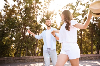Lovely young couple dancing together outdoors on sunny day