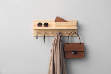 Wooden hanger for keys with different stuff on light grey wall