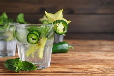 Spicy cocktail with jalapeno, carambola and mint on wooden table. Space for text