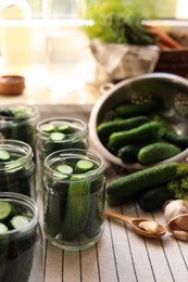 Photo of Glass jars with fresh cucumbers and other ingredients on table indoors. Canning vegetables