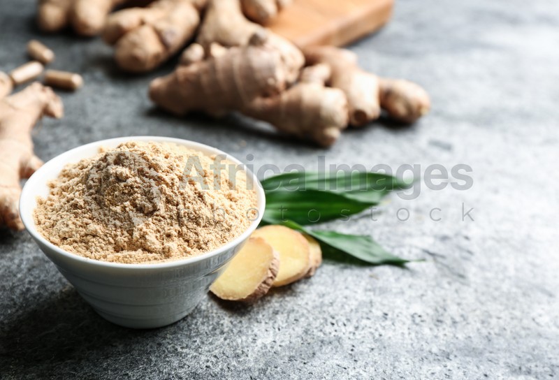 Dry ginger powder, fresh root and leaves on grey table. Space for text