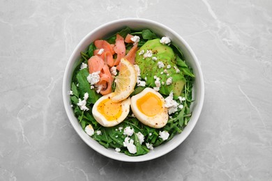 Photo of Delicious salad with boiled egg, salmon and cheese in bowl on light grey marble table, top view