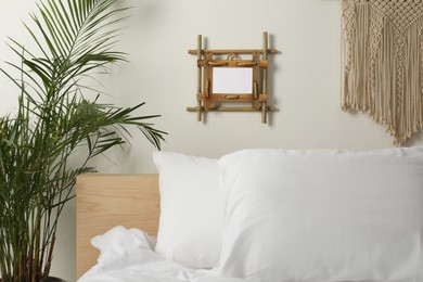 Empty bamboo frame hanging on white wall in bedroom