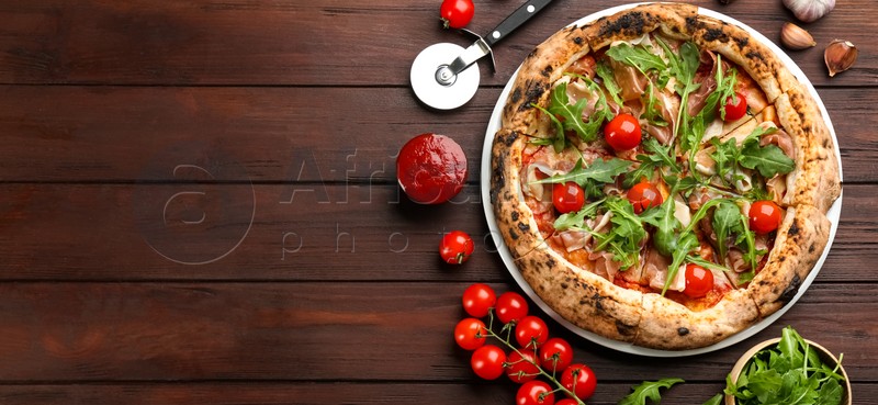 Photo of Tasty pizza with meat and arugula on wooden table, flat lay. Space for text