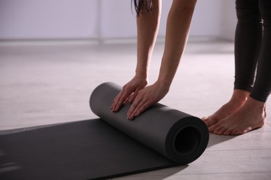 Photo of Woman rolling yoga mat in studio, closeup