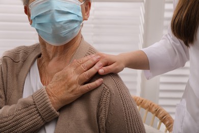 Photo of Doctor taking care of senior woman with protective mask at nursing home, closeup