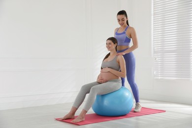 Trainer working with pregnant woman in gym. Preparation for child birth