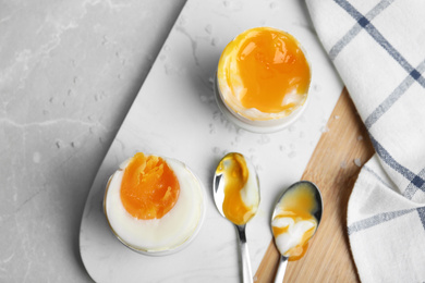 Soft and medium boiled chicken eggs on light grey marble table, flat lay