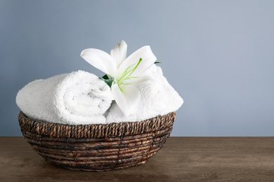 Fresh towels and lily flower on wooden table, space for text