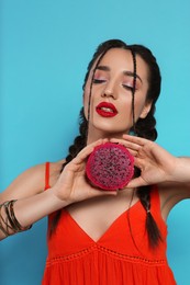 Young woman with fresh pitahaya on light blue background. Exotic fruit