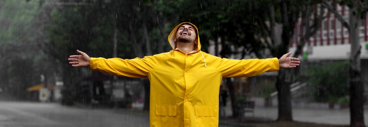 Image of Autumn season. Happy young man in bright coat outdoors on rainy day. Banner design