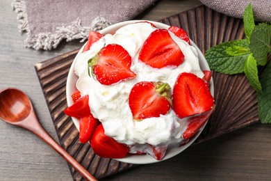 Delicious strawberries with whipped cream served on wooden table, flat lay