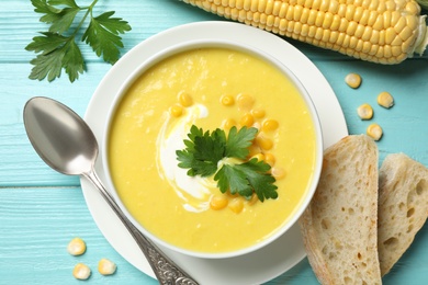 Delicious creamy corn soup served on turquoise wooden table, flat lay