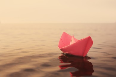 Pink paper boat floating on river. Retro photo effect