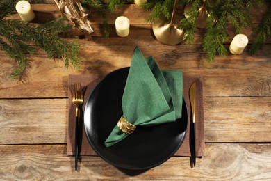 Photo of Stylish table setting with green fabric napkin, beautiful decorative ring and festive decor on wooden background, flat lay