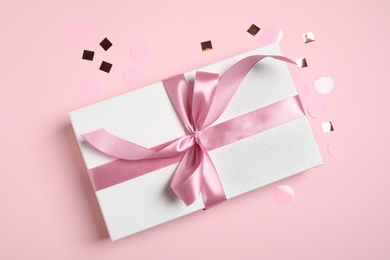 Photo of Beautiful gift box and confetti on pink background, flat lay