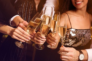 Friends with glasses of sparkling wine celebrating New Year, closeup