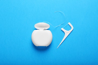 Photo of Container with dental floss and pick on light blue background, flat lay. Mouth hygiene