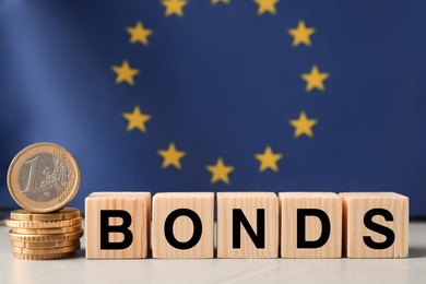 Photo of Word Bonds made of wooden cubes with letters and stacked coins against European union flag