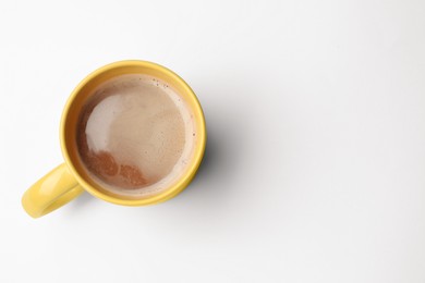 Yellow mug of freshly brewed hot coffee on white background, top view. Space for text