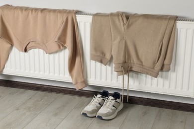 Heating radiator with sweatshirt, pants and sneakers indoors