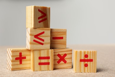 Photo of Wooden cubes with mathematical symbols on table against light background