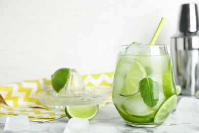 Delicious mojito and ingredients on white marble table. Space for text