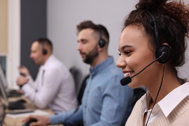 Photo of Call center operators working in modern office, focus on African American woman with headset