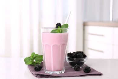 Tasty blackberry milk shake with fresh berries on white table