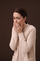 Woman coughing on brown background. Cold symptoms