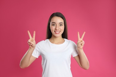 Woman showing number four with her hands on pink background