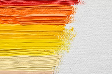 Photo of Beautiful strokes of colorful oil paints on white canvas, closeup. Space for text