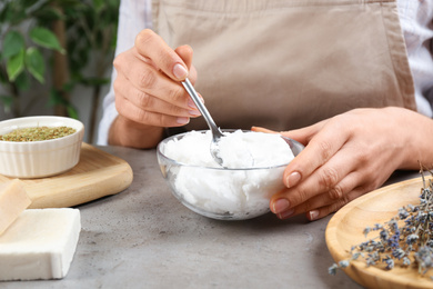 Woman making natural handmade soap at grey stone table, closeup