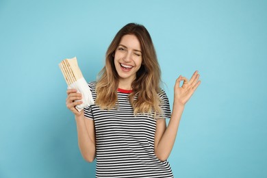 Photo of Young woman with delicious shawarma on turquoise background