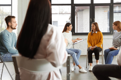 Psychotherapist working with patients in group therapy session indoors
