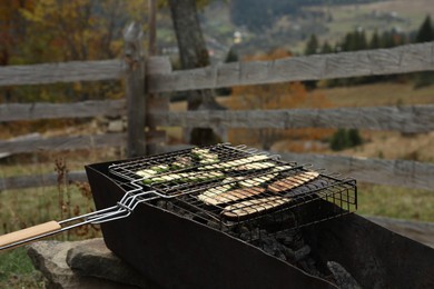 Cooking delicious vegetables on metal grid for barbecue outdoors