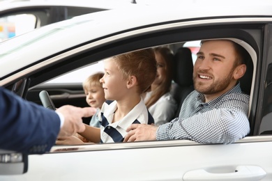 Young family choosing new car with salesman in salon