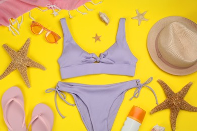 Flat lay composition with swimsuit and beach accessories on yellow background