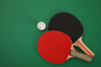 Rackets and ball on green background, flat lay. Ping pong