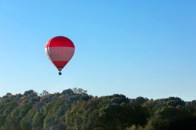 Beautiful view of hot air balloon flying over autumn forest. Space for text