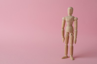 Wooden human model on pink background, space for text. Mini mannequin