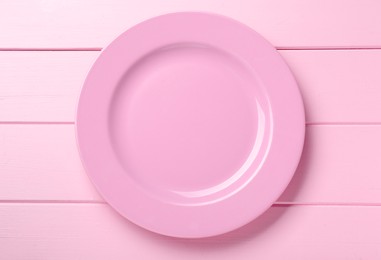 Photo of Empty ceramic plate on pink wooden table, top view