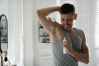 Handsome man applying deodorant in bathroom. Space for text