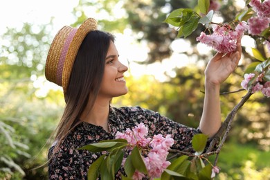 Beautiful young woman near blossoming sakura tree in park