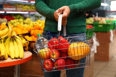 Man with shopping basket in supermarket, closeup